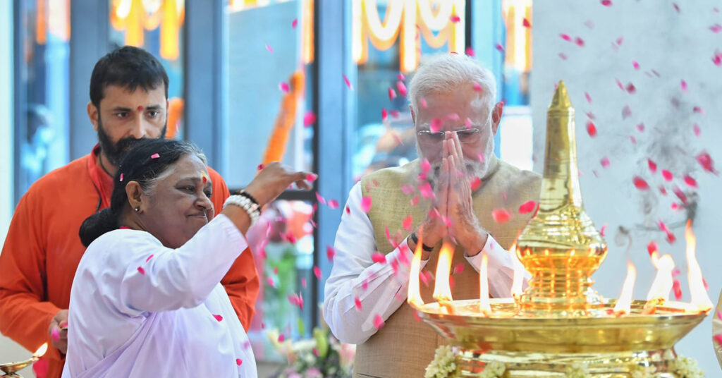 Amma throws flowers around the oil lamp