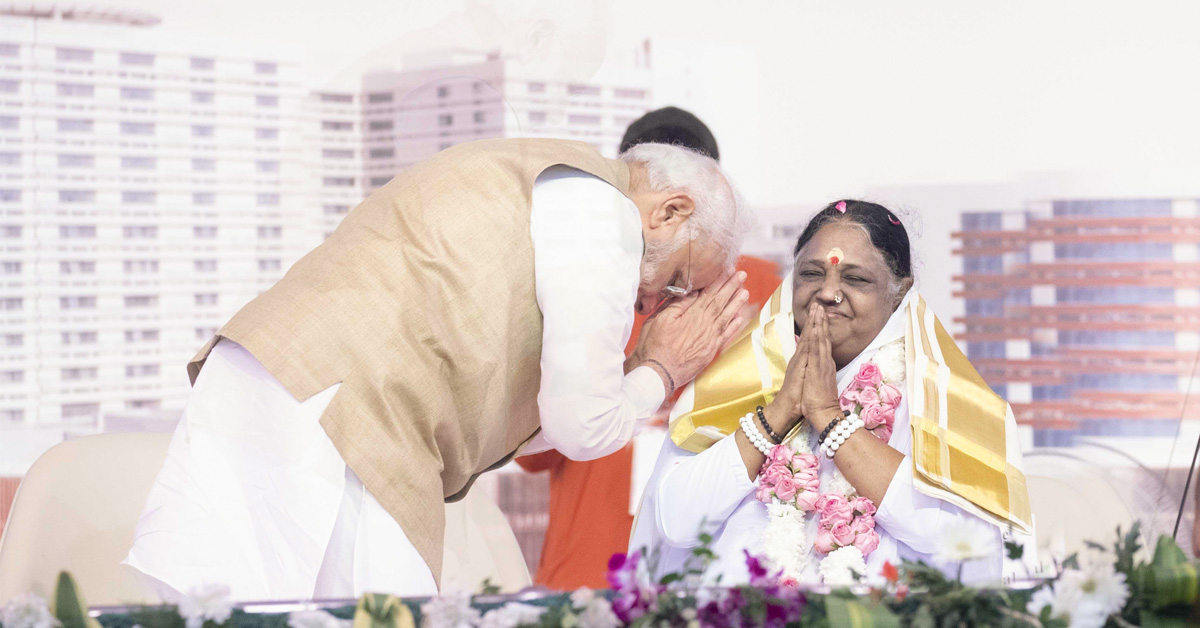 Prime Minister Narendra Modi, with his hands folded, bowing to Amma while she smiles back at him with her own hands folded in humility.