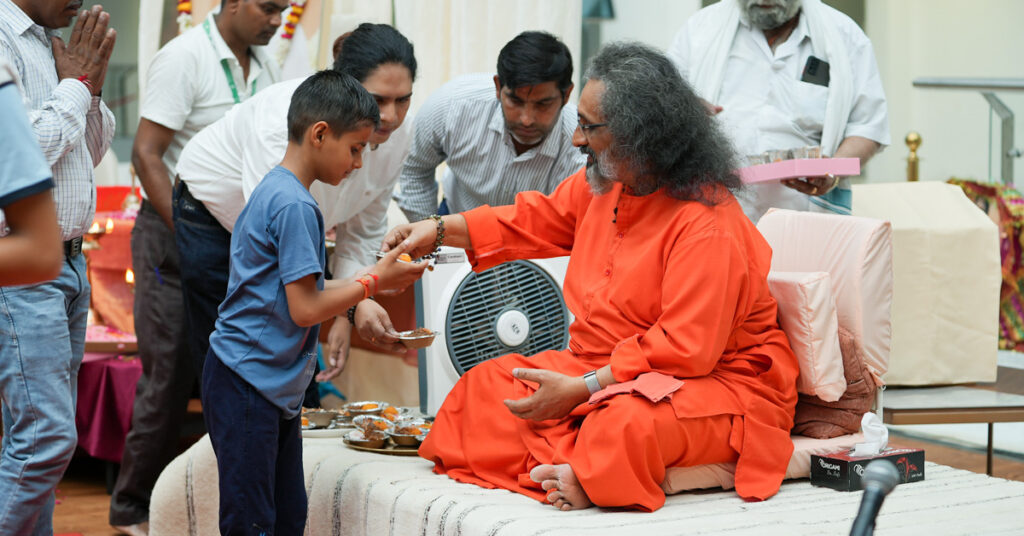 A child receives prasad from Swamiji