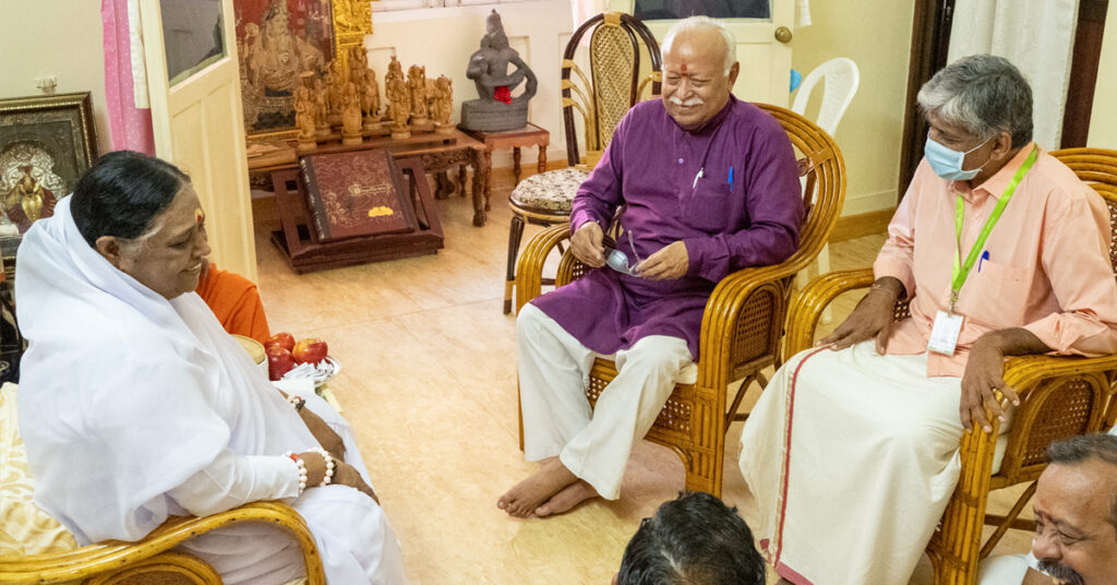 Amma sitting across from Dr. Bhagwat and another dignitary.