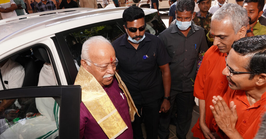 Dr. Bhagwat getting out of his car upon arrival at MAM being greeted by two Swamis.