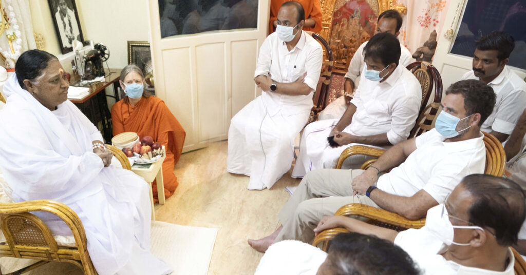 Amma sitting across from Mr. Gandhi along with other dignitaries.