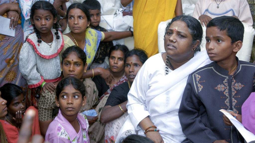 Amma sits with children