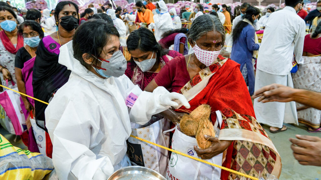 A woman in a mask and PPE suit distributes supplies