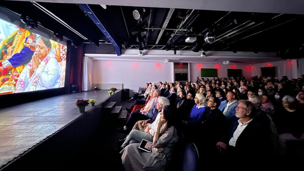 A prosenium stage lights up with a screening of Amma's Way and a very attentive audience.