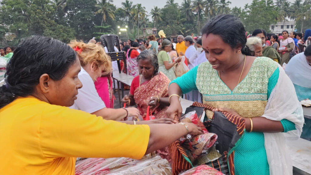 Female monastic from Amritapuri Ashram hands out saris