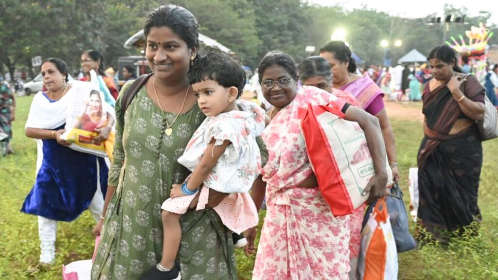 Women hold their baby in one arm and their bags of aid in the other