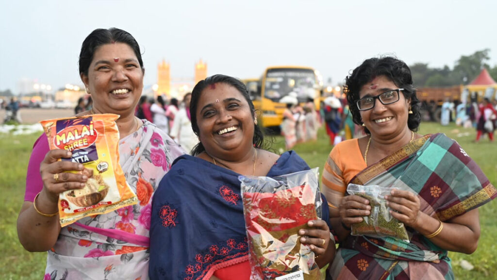 Women hold up the food they received and smile