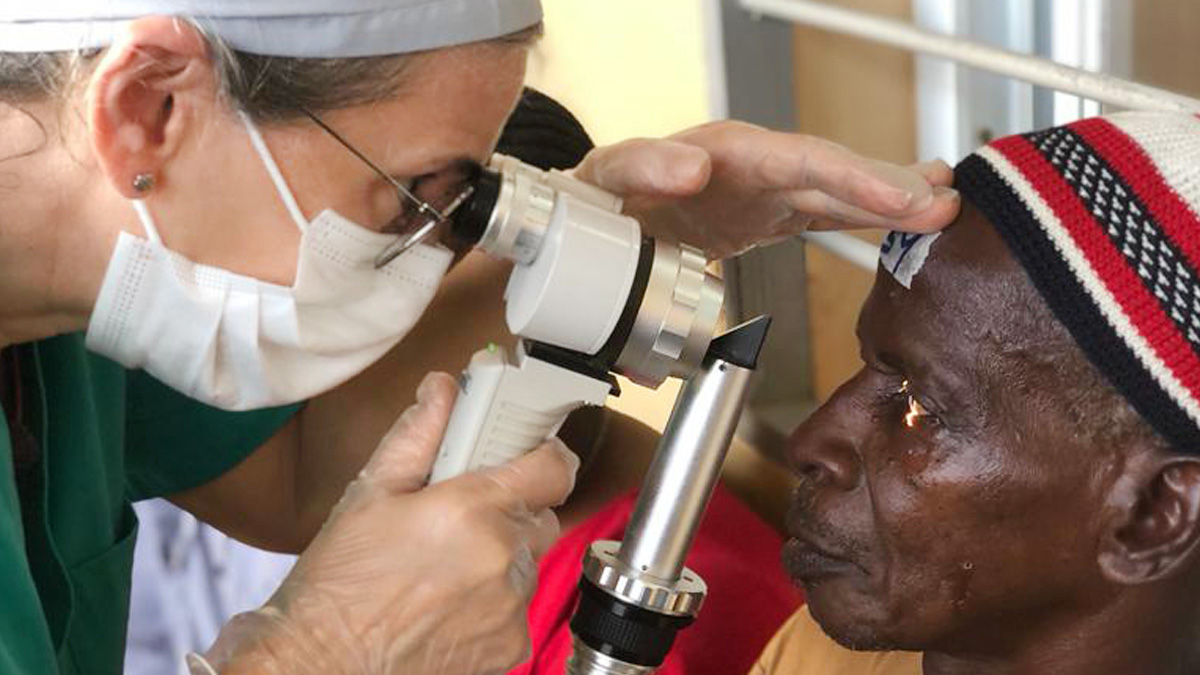 A doctor holds a medical device while examining the eyes of a patient