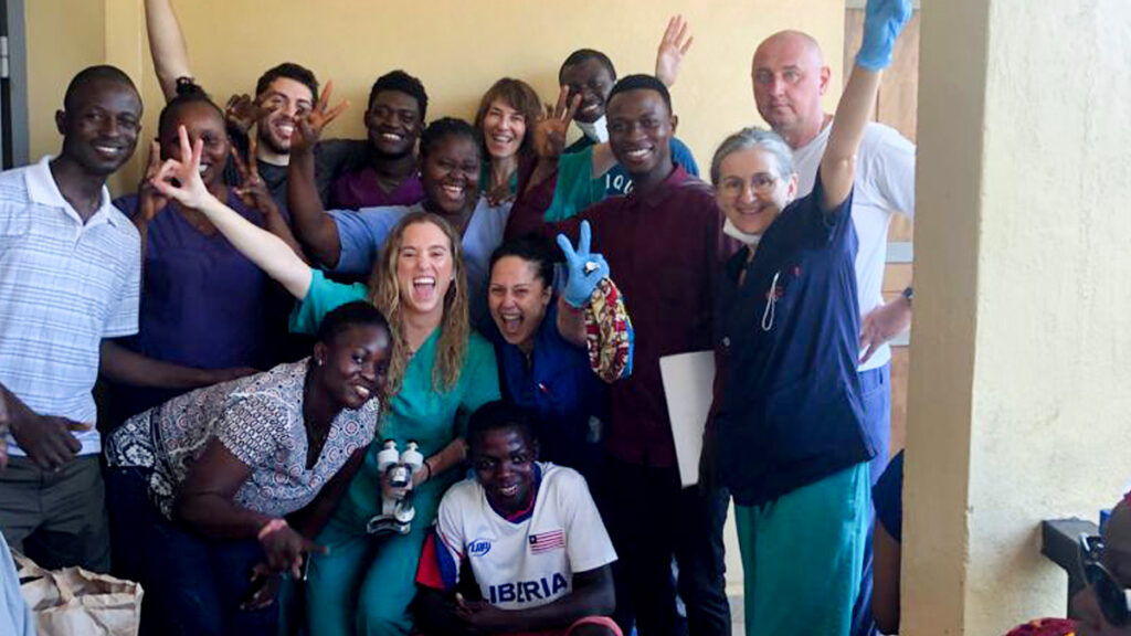 14 people on the team gather to pose while smiling for the camera