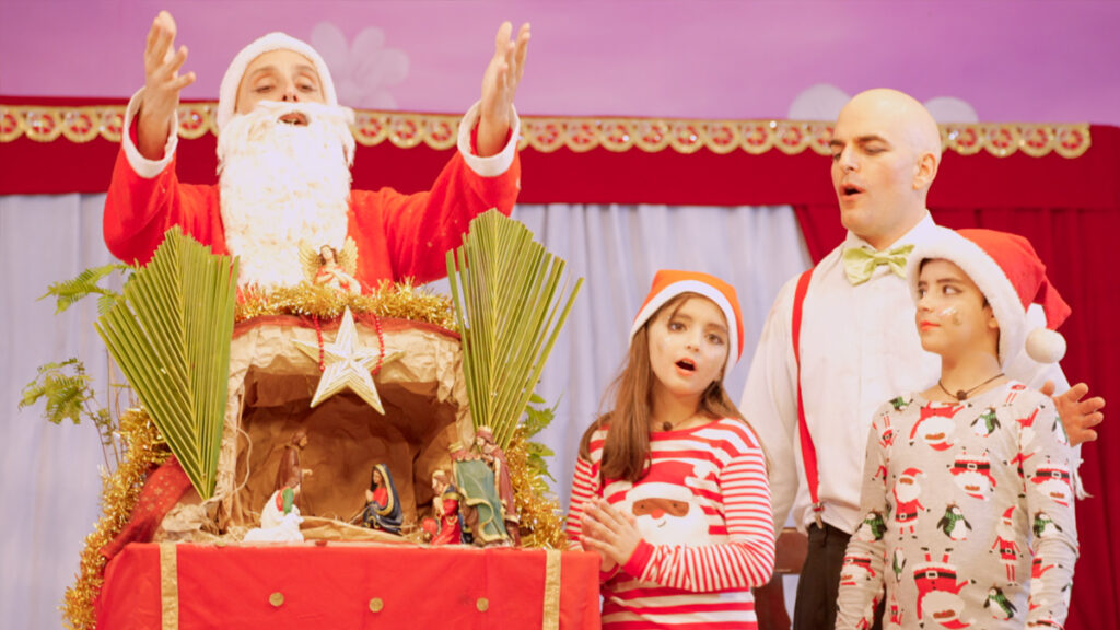 actors in one of the performances: Santa Claus talking to two children and an adult standing next to him