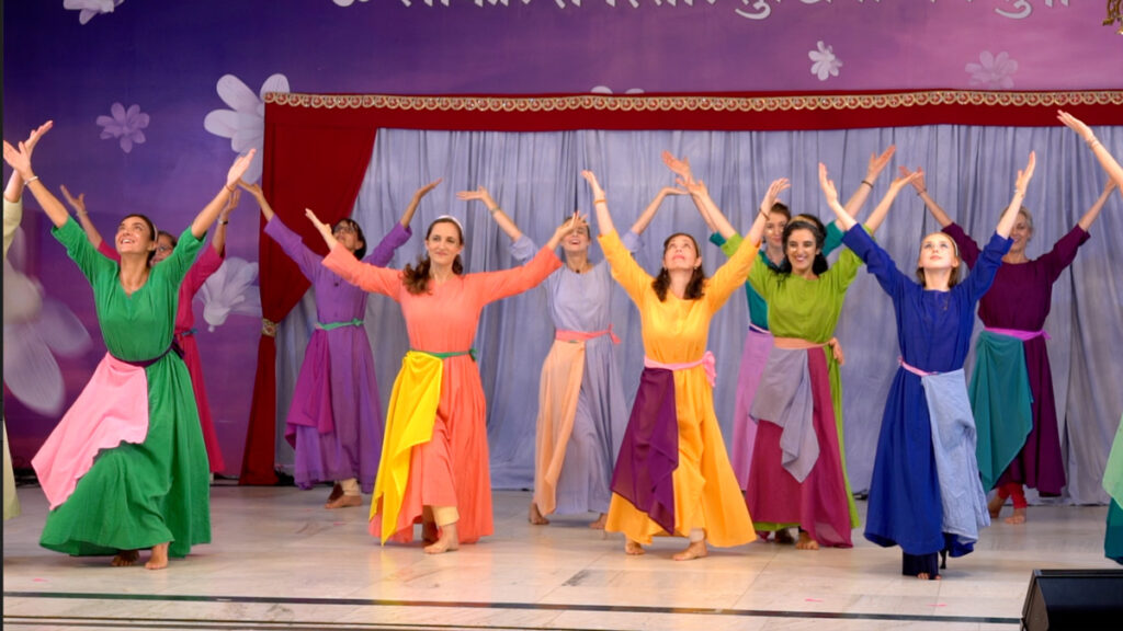 dancers in costume with arms raised high in celebration