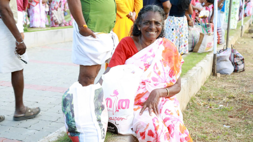 Woman sits, smiling, with her bag of aid