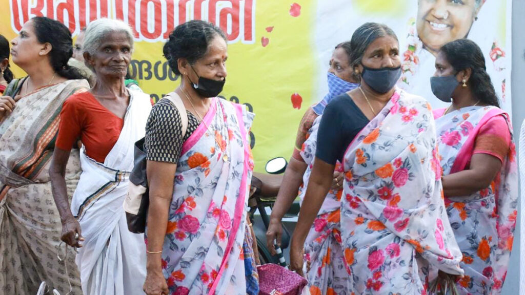 Women in matching saris and masks wait in line