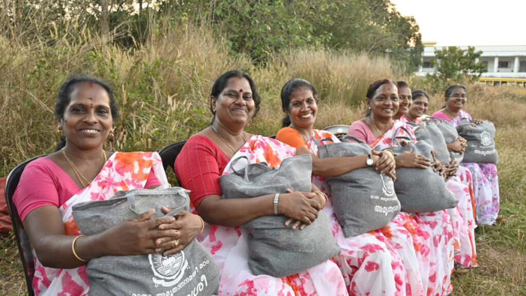 A row of women sit and smile, each holding a bag of aid