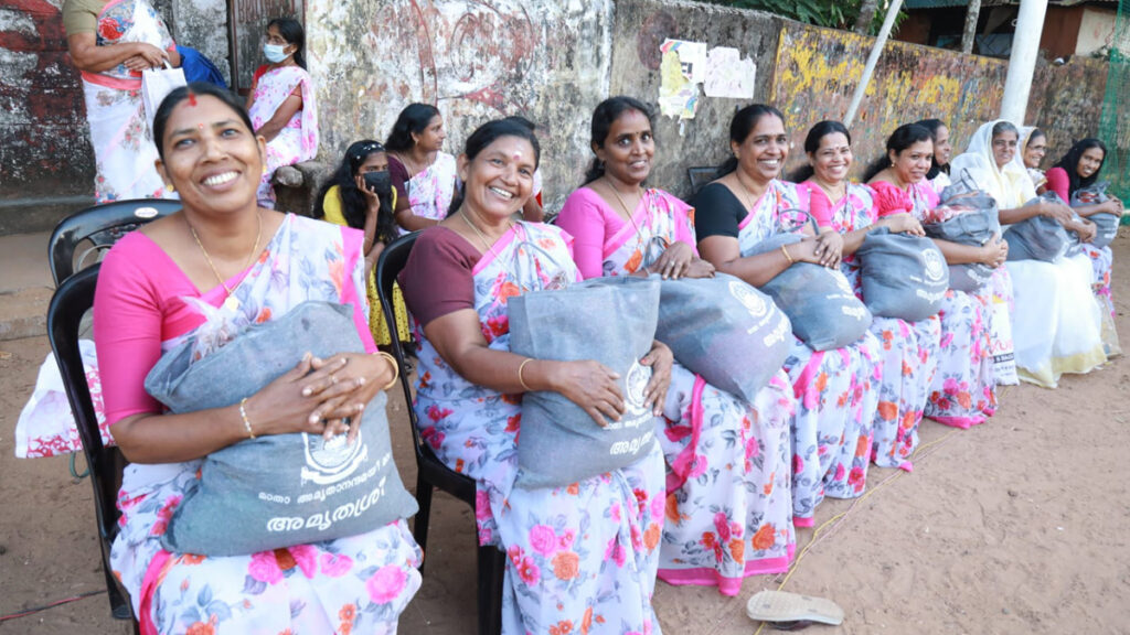 A row of women in matching saris smile at the camera