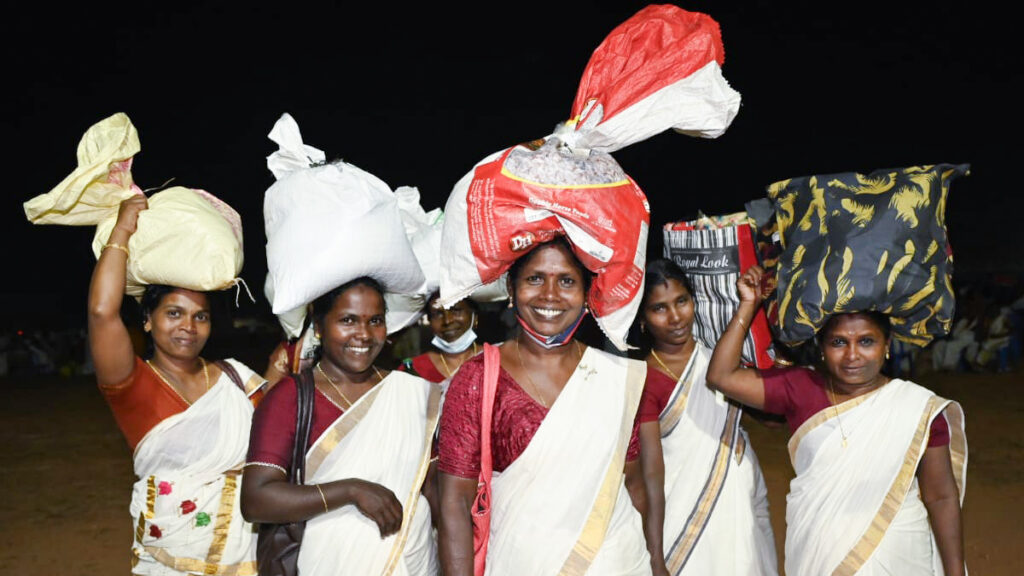 5 smiling women holding up there sacks of supplies.