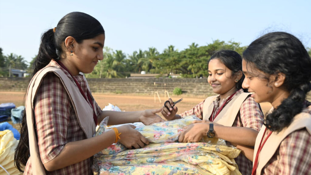 Three girls in school outfits helping to organize some of the supplies to be distributed.