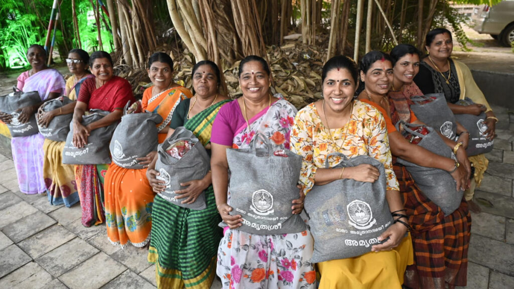 Women sit together and smile with their bags