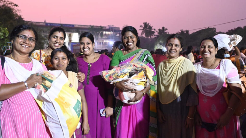 Women smile, holding their heavy bags of supplies