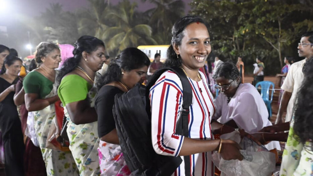 A woman smiles as she holds out her bag to receive aid