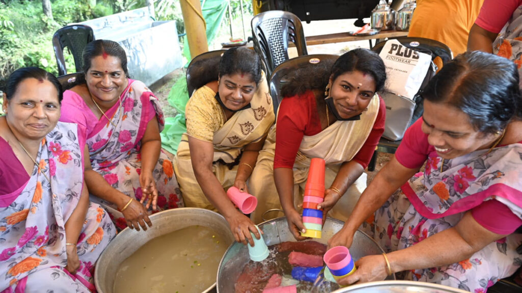 Women volunteers wash cups during the event with big smiles on their faces