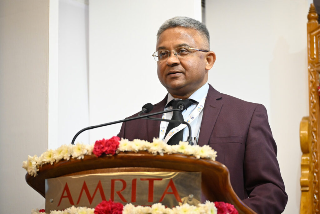 Sri Thakur, chief guest, at the podium in a brown suit encouraging the completely non-commercial, public-service approach to technological advancement.