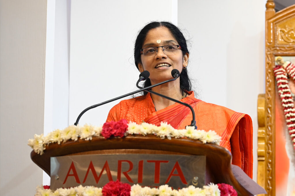 Dr Krishnasree Achuthan at the podium in a beautiful orange sari reiterated technology policies must be grounded in compassion.