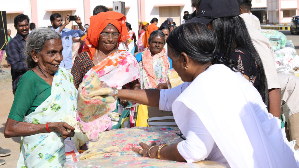 Older women line up to happily receive a new sari from a monastic.