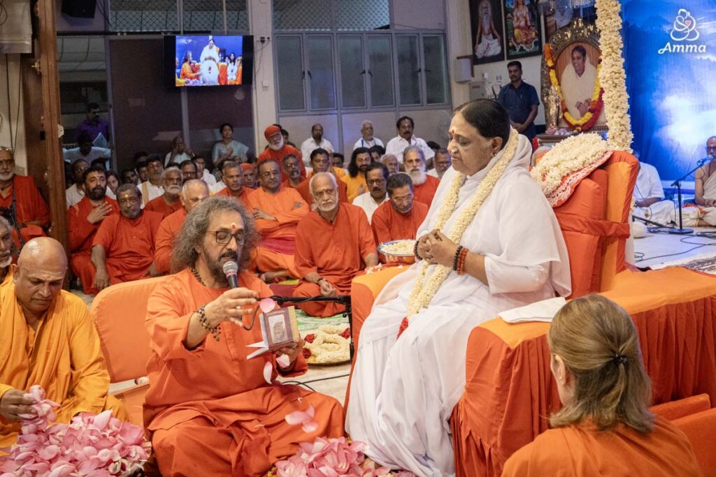 A Swami performs pada puja to Amma