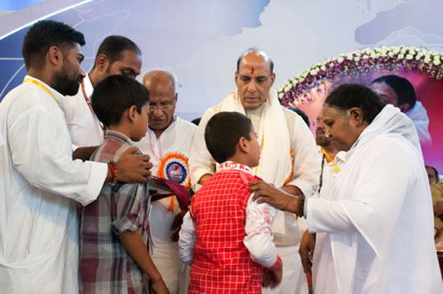 Amma, on stage, hands over scholarships to children alongside the minister