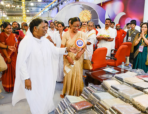 Amma stands next to the saris preparing to give them away