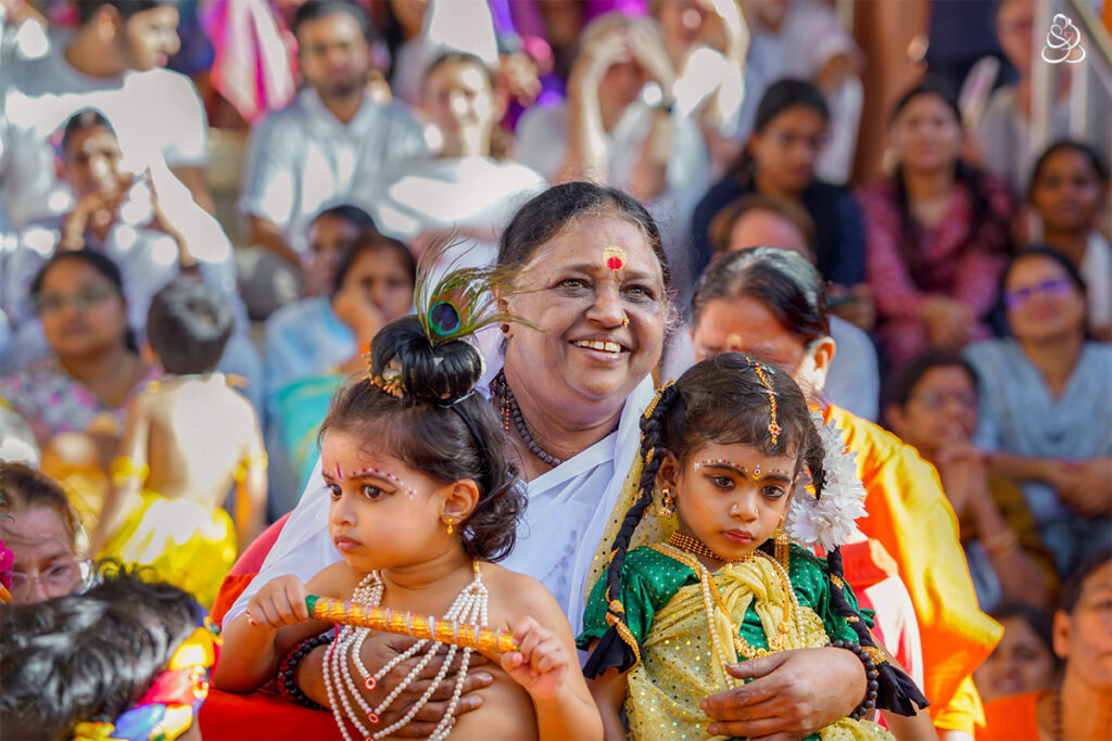 Amma with two small children dressed as Krishna and Radha on her lap