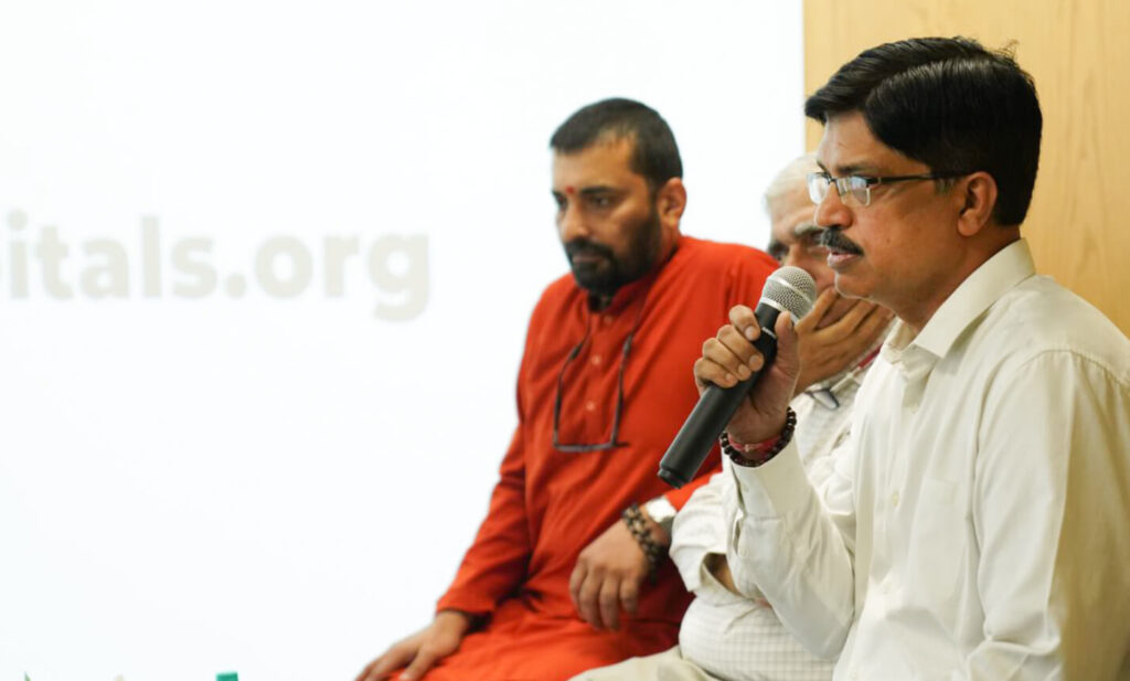 Dr. Singh, Medical Director of Amrita Hospital, Faridabad, speaks seated with Dr. Prem Nair and Amma's monastic Swami.