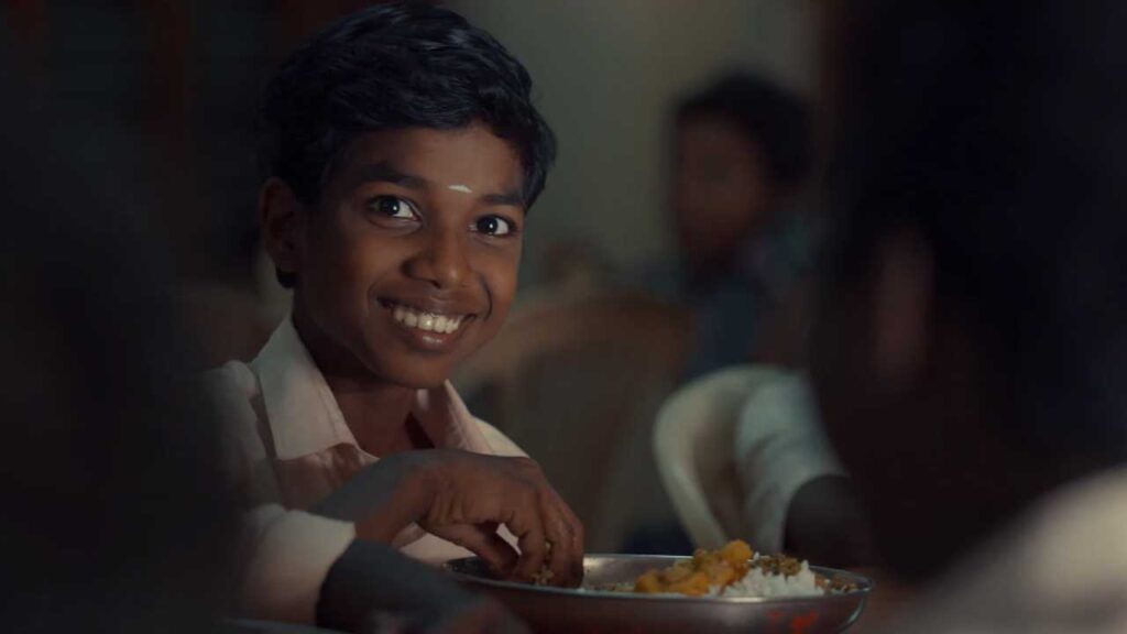 Child eats and smiles at camera