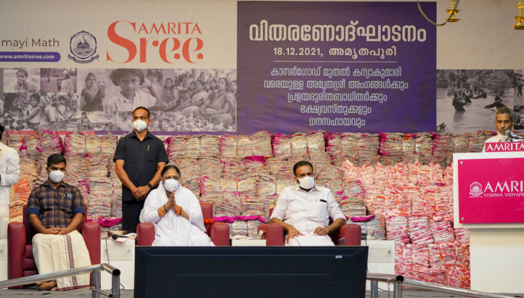 Amma sits in front of many saris