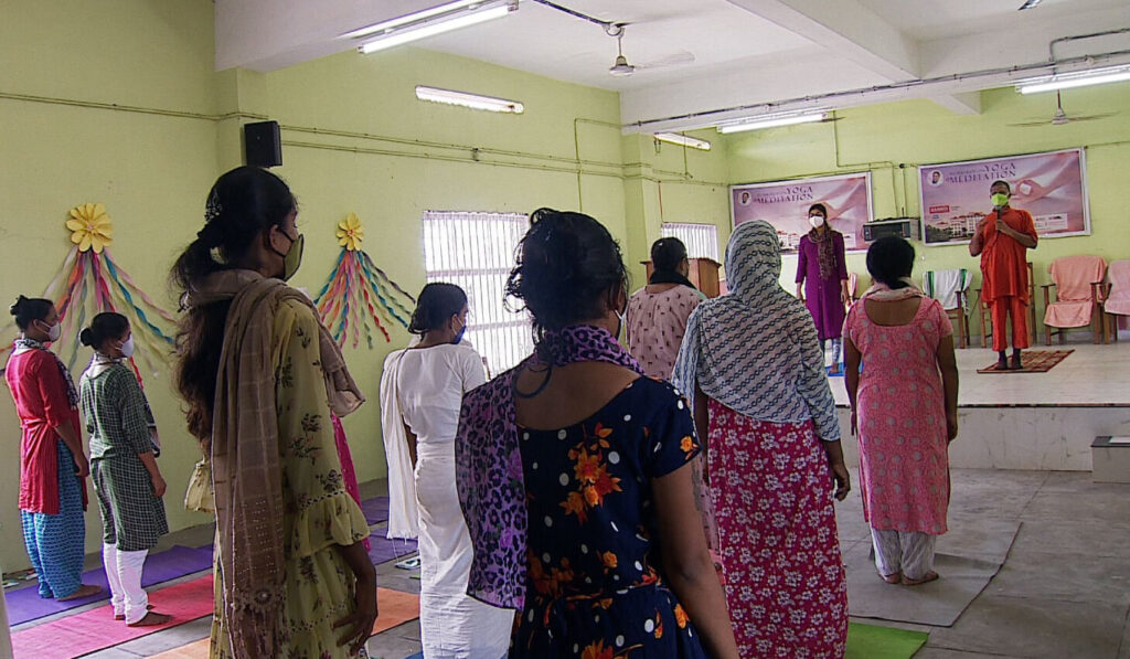 Women stand in mountain posture also known as the yoga asana Tadasana.