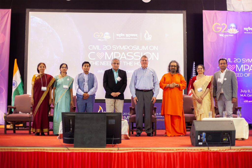 Dignitaries and speakers gather with Swami Amritaswarupananda Puri on stage.