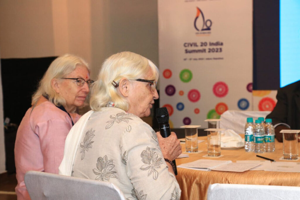 A participant seated at a table takes the mic to ask a question