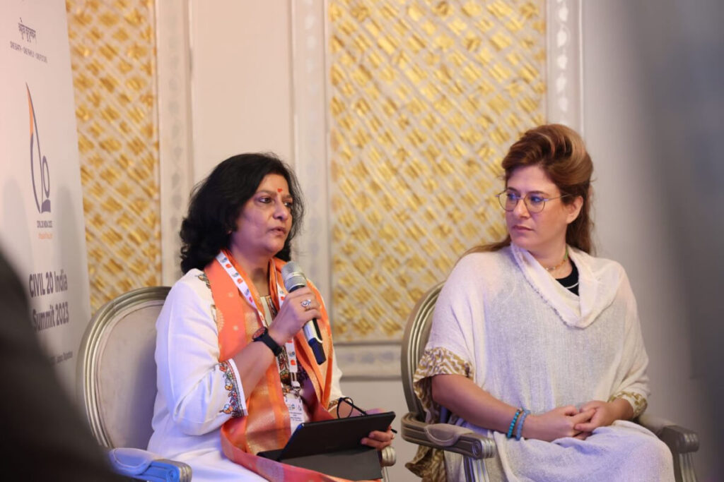 A seated speaker engages in discussion while another woman looks on