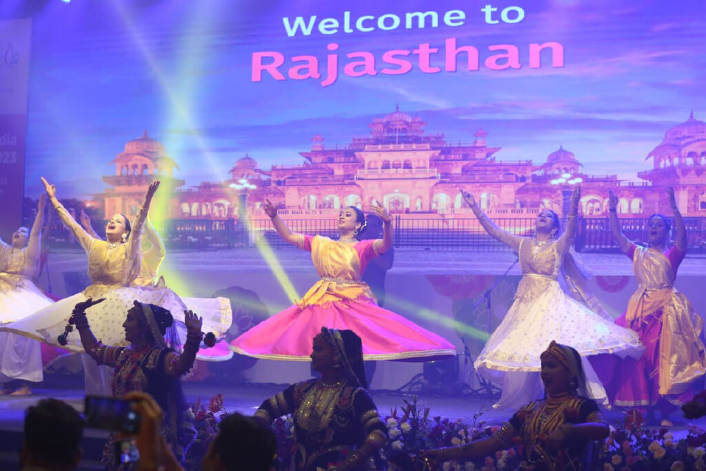 Dancers perform before a backdrop reading "Welcome to Rajasthan"