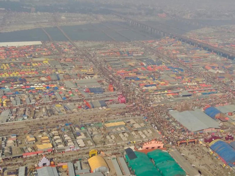 aerial view of the Kumbh Mela grounds filled with many tents of various sizes. the ganges is in the distance.