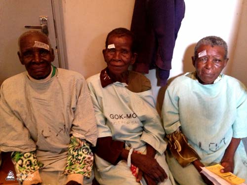 Three recipients of surgery sit with small bandages on their foreheads