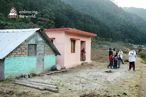 Volunteers and villagers stand next to new house