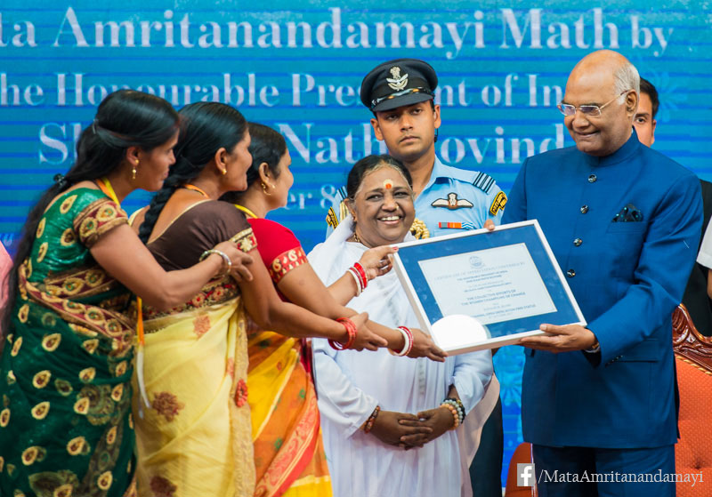 Amma stands next to the president as he hands over a certificate