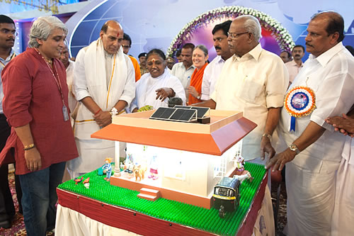 Amma looks at a solar panel model and talks to dignitaries about it