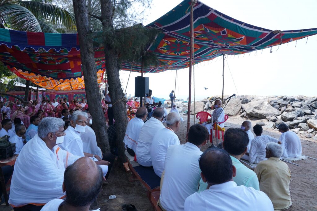 members of the group sitting under a shade cloth on the beach