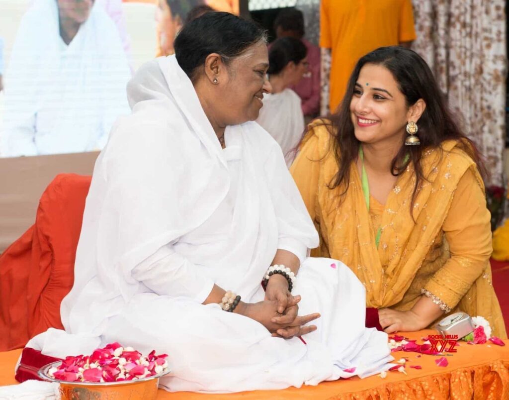 Amma and actor Vidya Balan sit and smile at each other.