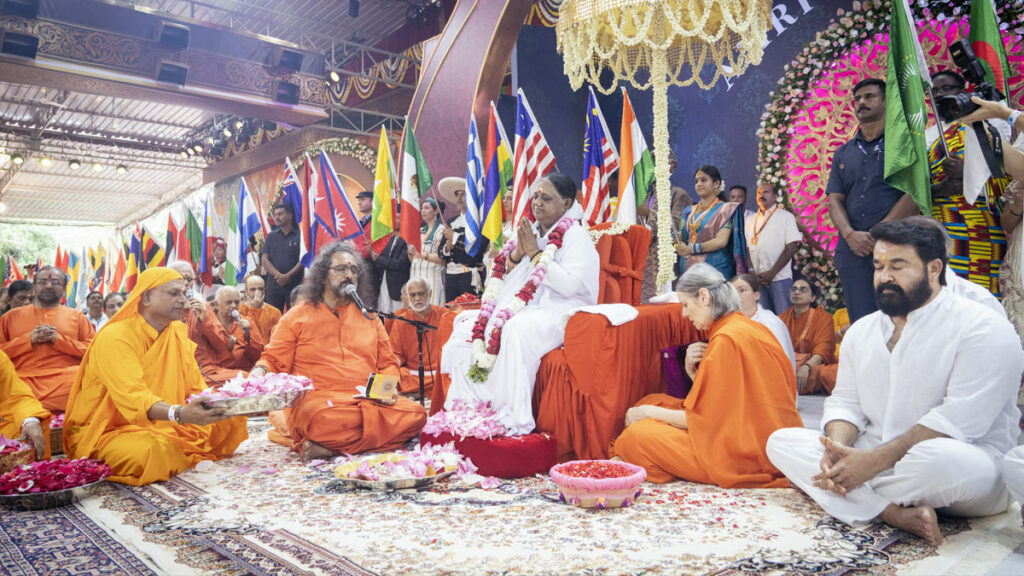 Amma sits on the stage, surrounded by ashram disciples