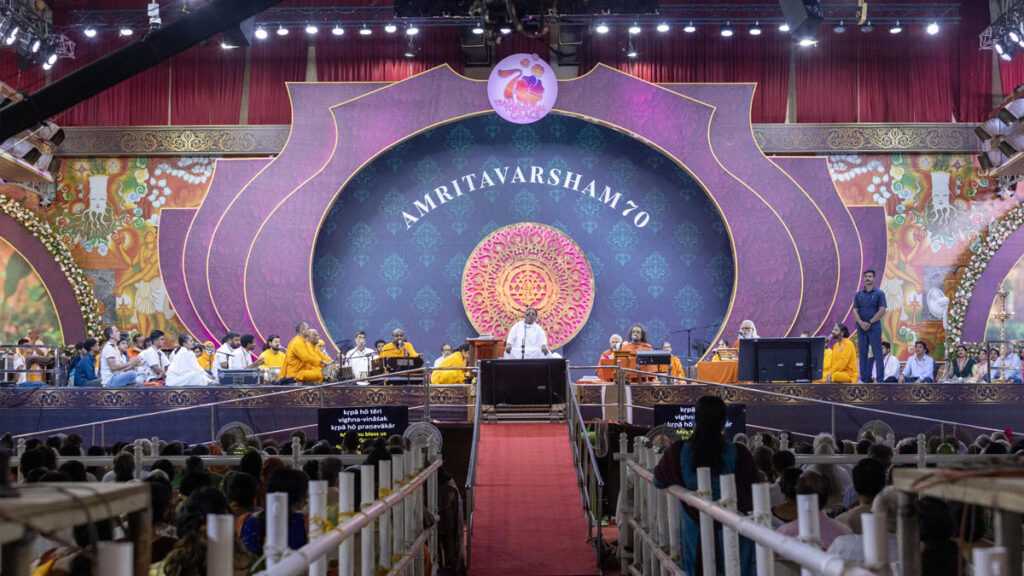 Amma sings bhajans on a large, decorated stage